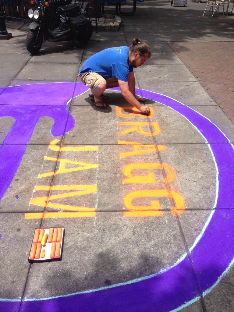a man colors in letters with chalk