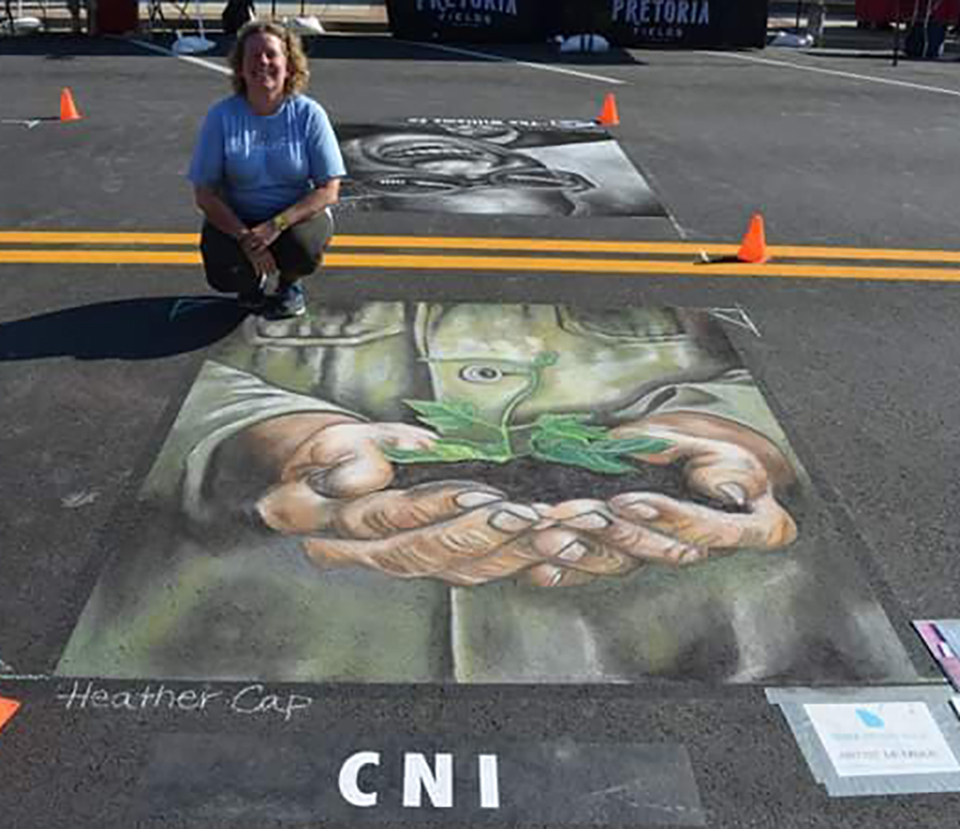 Heather Cap A chalk drawing of hands holding a growing tree and artist Heather Cap.